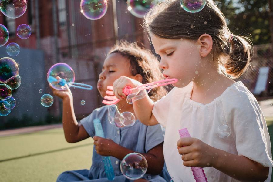 Two girls chasing bubbles in a garden