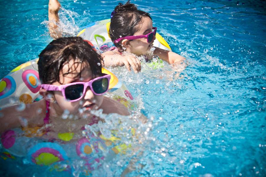A kid in sunglasses floating in the pool