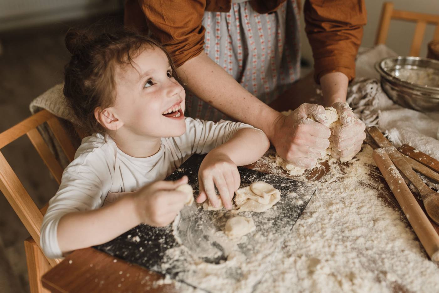 A little girl laughing while baking with her mom